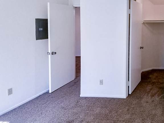 A room with a carpeted floor and two open doors.
