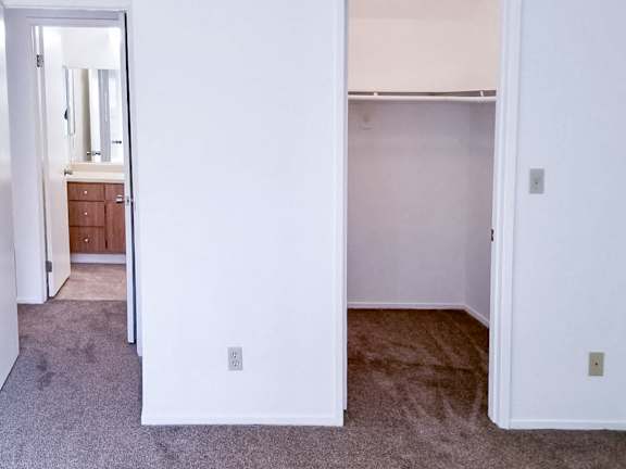 A carpeted room with a doorway leading to another room.