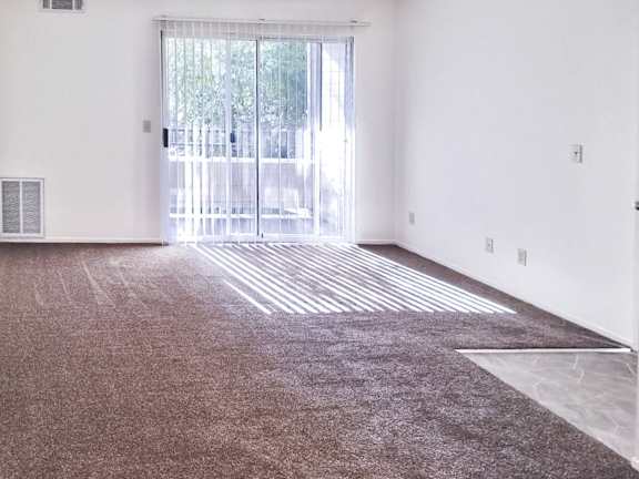 A room with a carpeted floor and a sliding glass door.