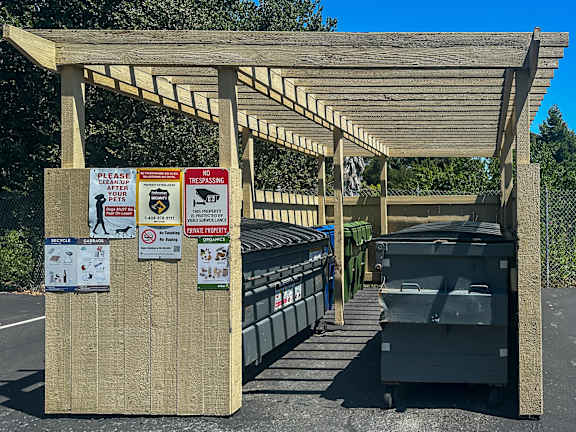 A wooden shelter with multiple signs attached to it.