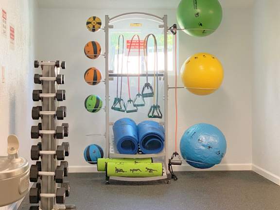 A gym with a variety of equipment including dumbbells, resistance bands, and exercise balls.