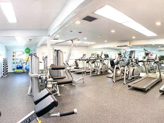 A gym with a variety of equipment including treadmills, weights, and exercise machines.