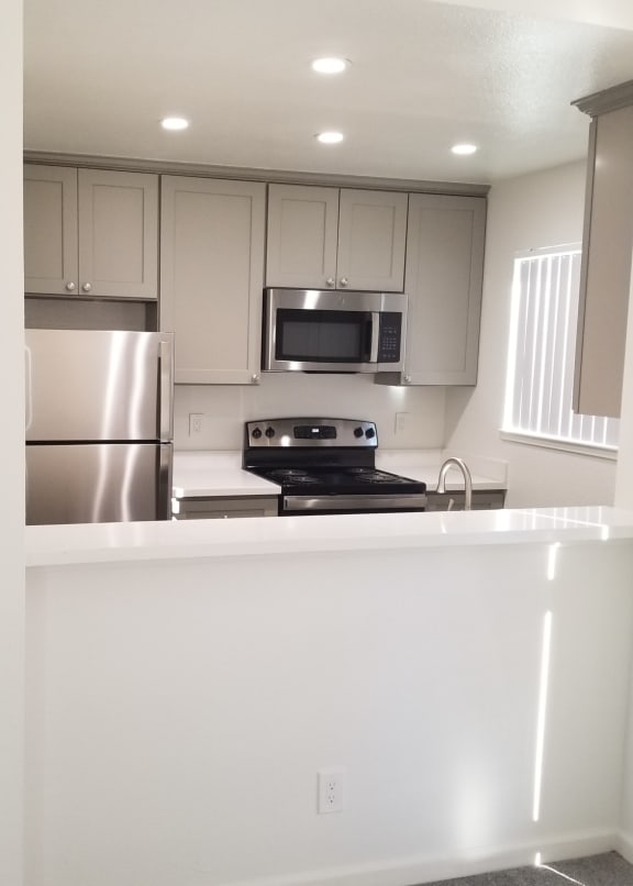 a kitchen with white cabinets and stainless steel appliances