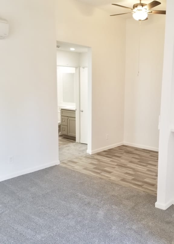 an empty living room with a ceiling fan and white walls