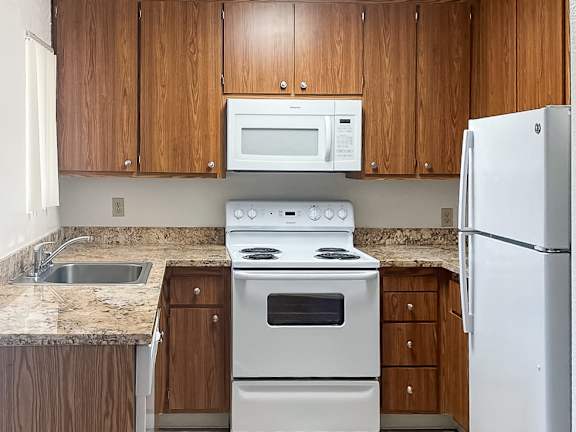 A kitchen with a white stove and refrigerator.