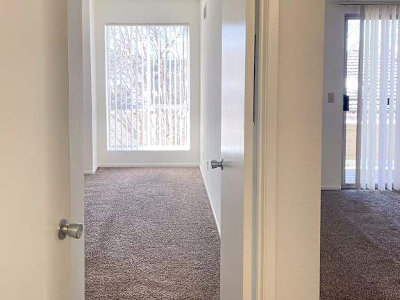 A hallway with a carpeted floor and a door on the left.