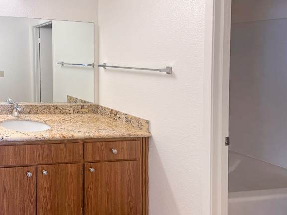 A bathroom with a sink, mirror, and wooden cabinets.