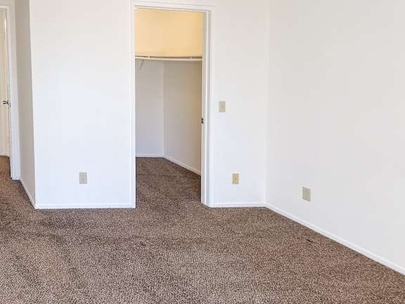 A carpeted room with a doorway leading to another room.