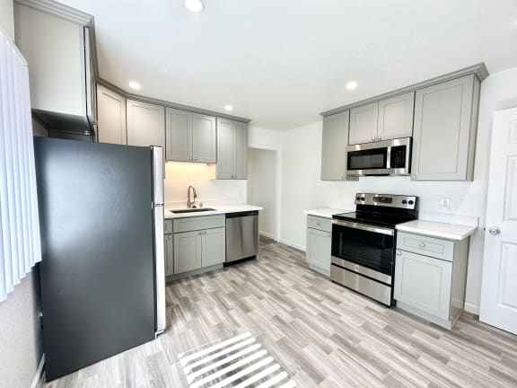 a kitchen with gray cabinets and a black refrigerator