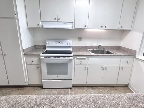 an empty kitchen with white cabinets and white appliances