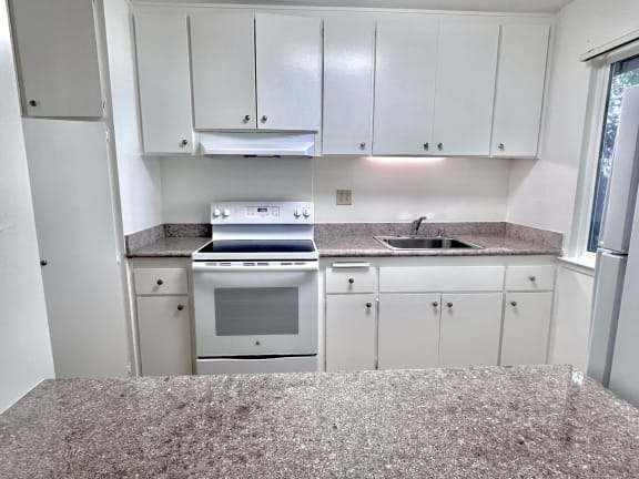 an empty kitchen with white cabinets and white appliances