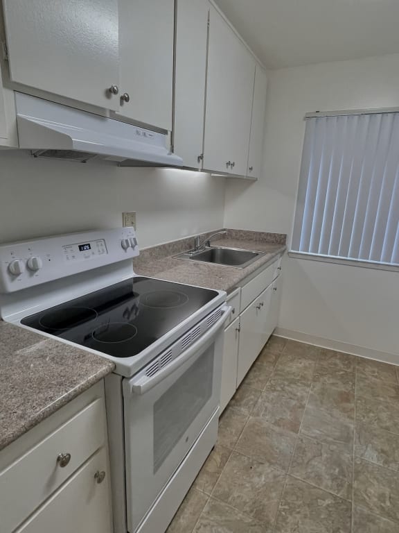 an empty kitchen with white appliances and granite countertops