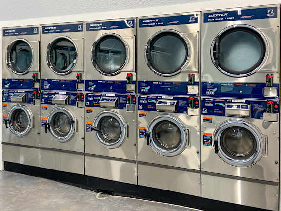 A row of industrial washing machines are lined up in a row.