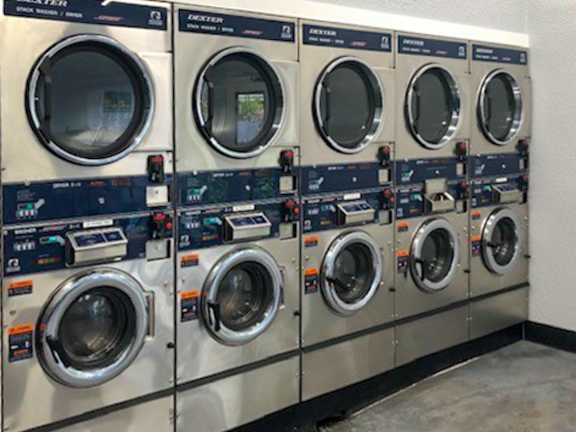 A row of industrial washing machines are lined up in a row.