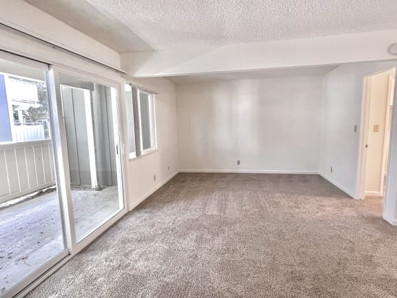 an empty living room with a sliding glass door and a patio