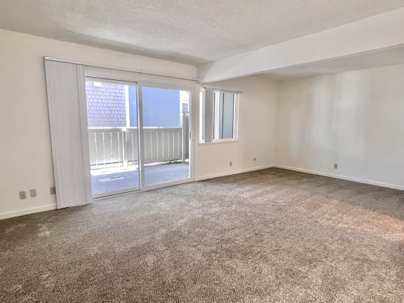 an empty living room with a sliding glass door and a balcony