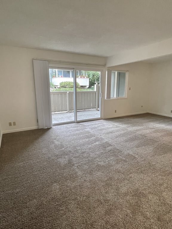 an empty living room with a sliding glass door and a balcony