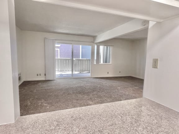 an empty living room with a sliding glass door and a balcony