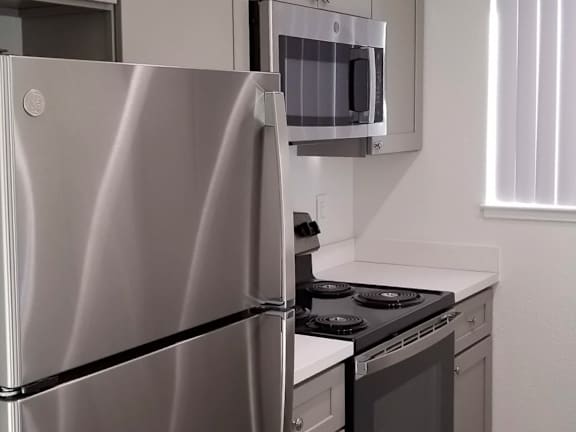 A stainless steel refrigerator stands in a kitchen next to a stove.