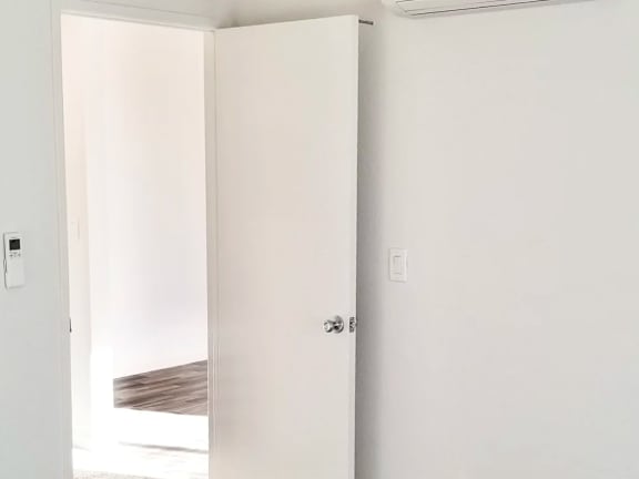 A white door is open to a room with a wooden floor.