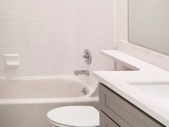 A white toilet sits next to a bathtub in a bathroom.