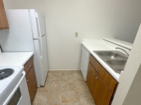 A kitchen with a white fridge, stove, and sink.