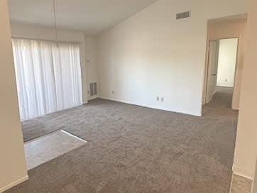 A room with a carpeted floor and a window with curtains.