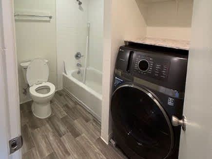 A small bathroom with a toilet, a washing machine, and a bathtub.