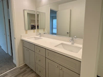 A bathroom with a vanity, sink, and mirror.