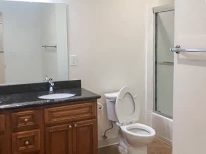 A white toilet sits in a bathroom next to a sink.