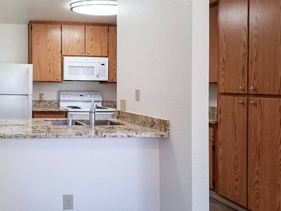 A kitchen with a white fridge, microwave, and oven.