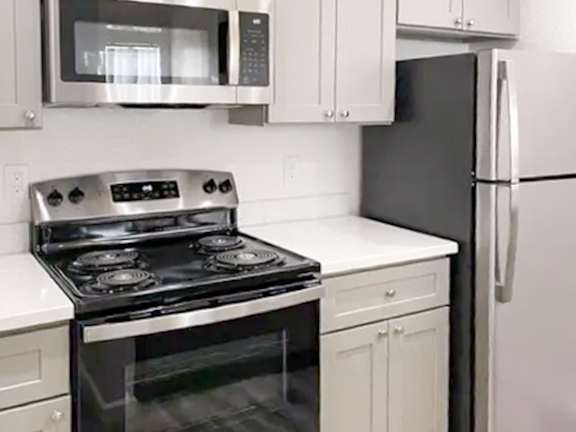A black stove top oven with four burners and a white oven with a glass door.