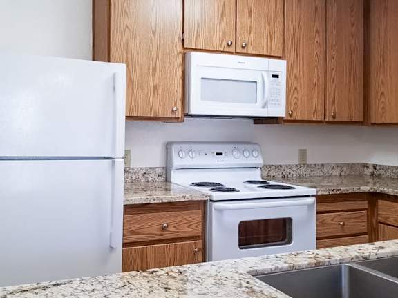 A white refrigerator and a white microwave are in a kitchen.
