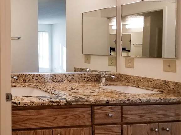 A bathroom with granite countertops and wooden drawers.