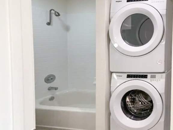 A white washing machine and a bathtub with a shower head in a bathroom.