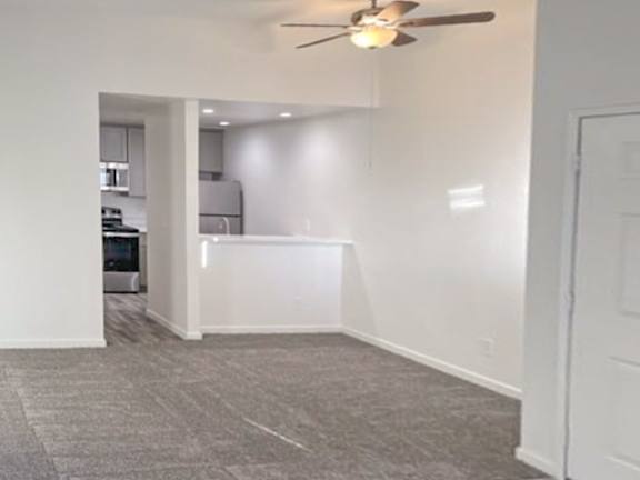 A room with a ceiling fan and carpeted floor.