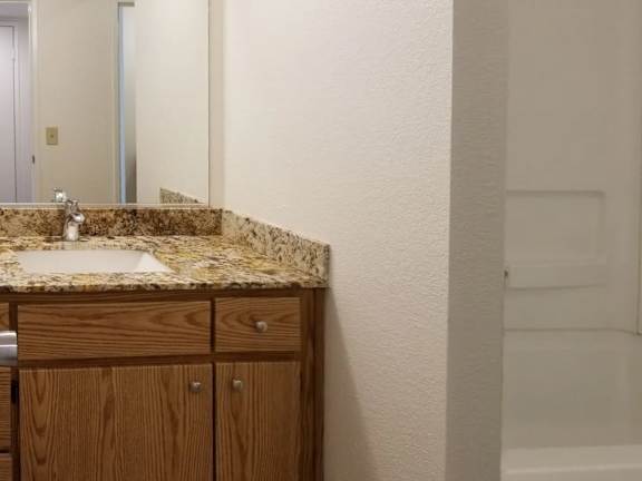 A bathroom with a sink and wooden cabinets.