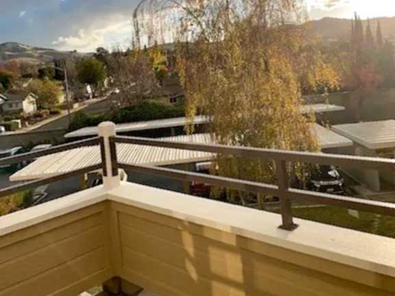 A balcony with a railing overlooking a street with cars and houses.