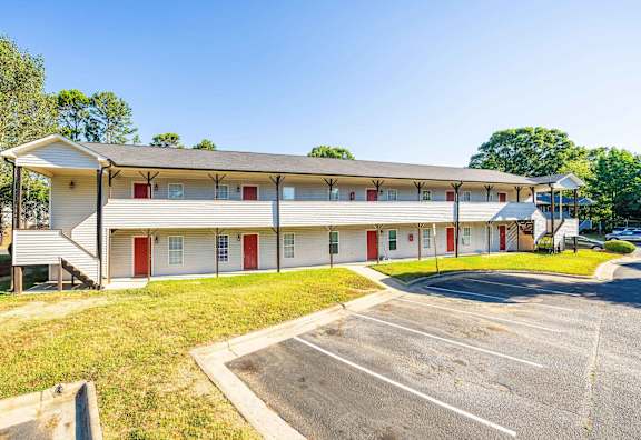 a large white building with red doors and a parking lot