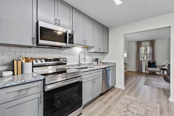 A modern kitchen with a black oven and grey cabinets at West Oak Apartments, Wake Forest, NC