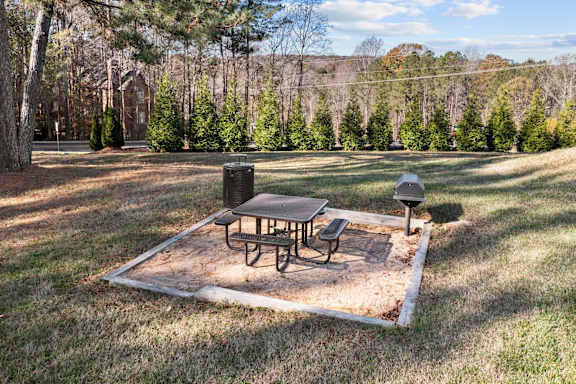 A picnic table and two chairs are set up on a picnic table in a grassy area at West Oak Apartments, Wake Forest, 27587