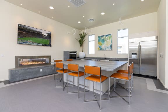 resident gathering room with large table with orange chairs in a room with a fireplace and television at Element 12 Henderson Nevada