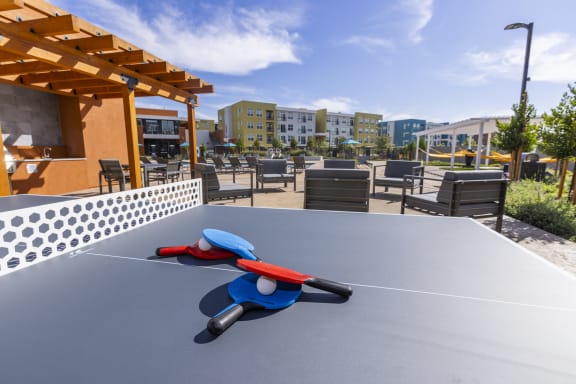 a ping pong table in a patio area with tables and chairs