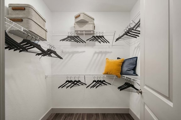 a hanger rack in a walk in closet with a yellow pillow at Element 12 Apartments in Henderson, NV