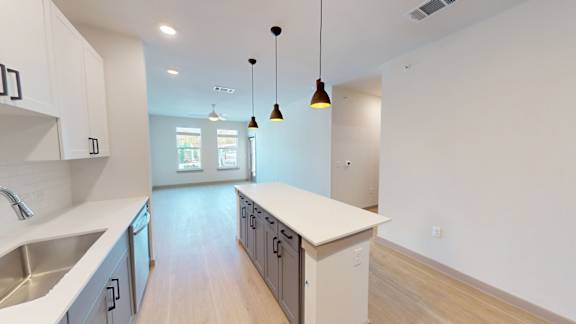 A kitchen with a sink, cabinets, and a counter.