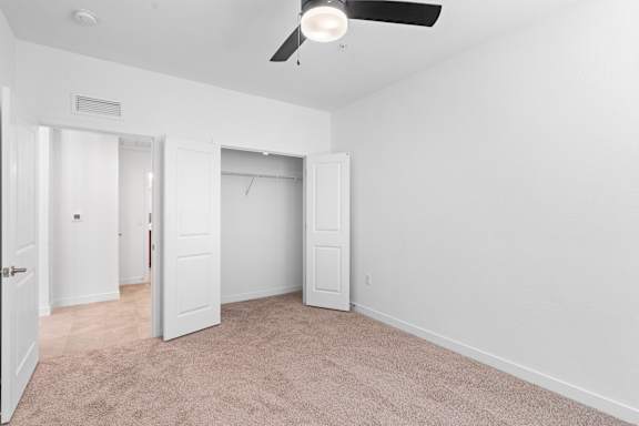 A room with a ceiling fan and carpeted floor.