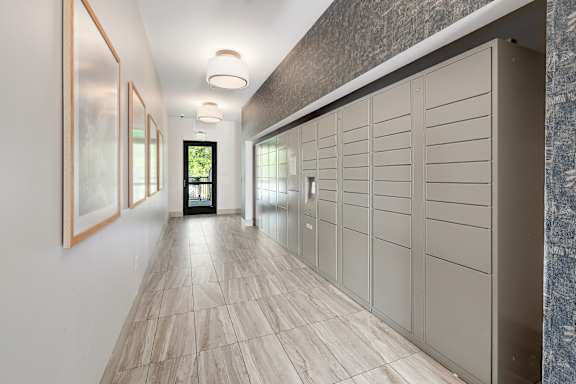 A hallway with a row of pictures on the wall and a row of cupboards on the other side.