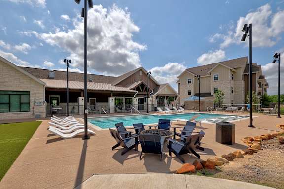 A pool area with lounge chairs and a building in the background.