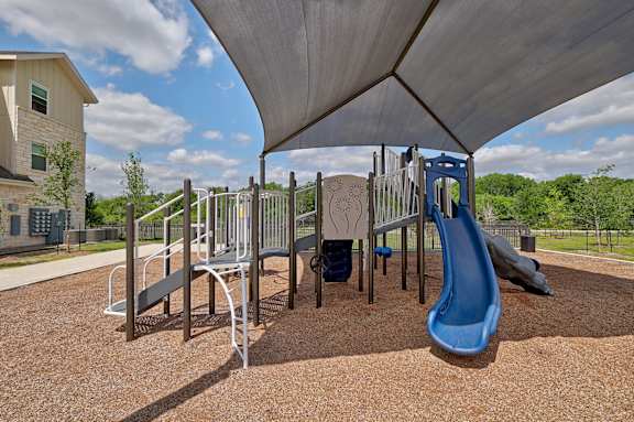 A playground with a blue slide and a brown surface.