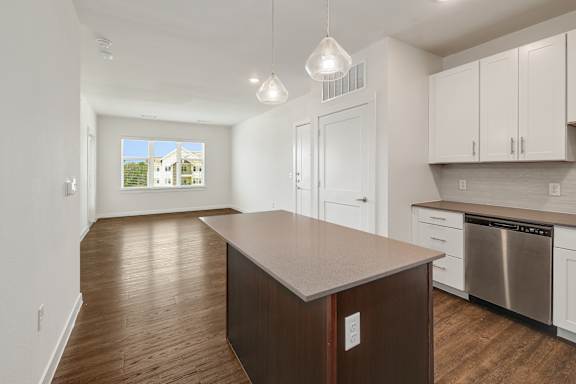A kitchen with white cabinets and a wooden island.